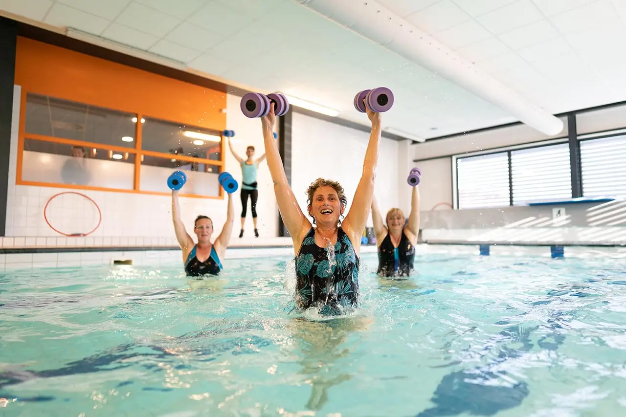 Groep doet aquafit met de armen omhoog