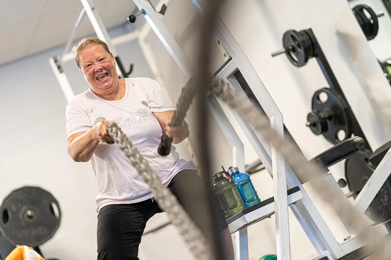 Sporter traint lachend met battle ropes