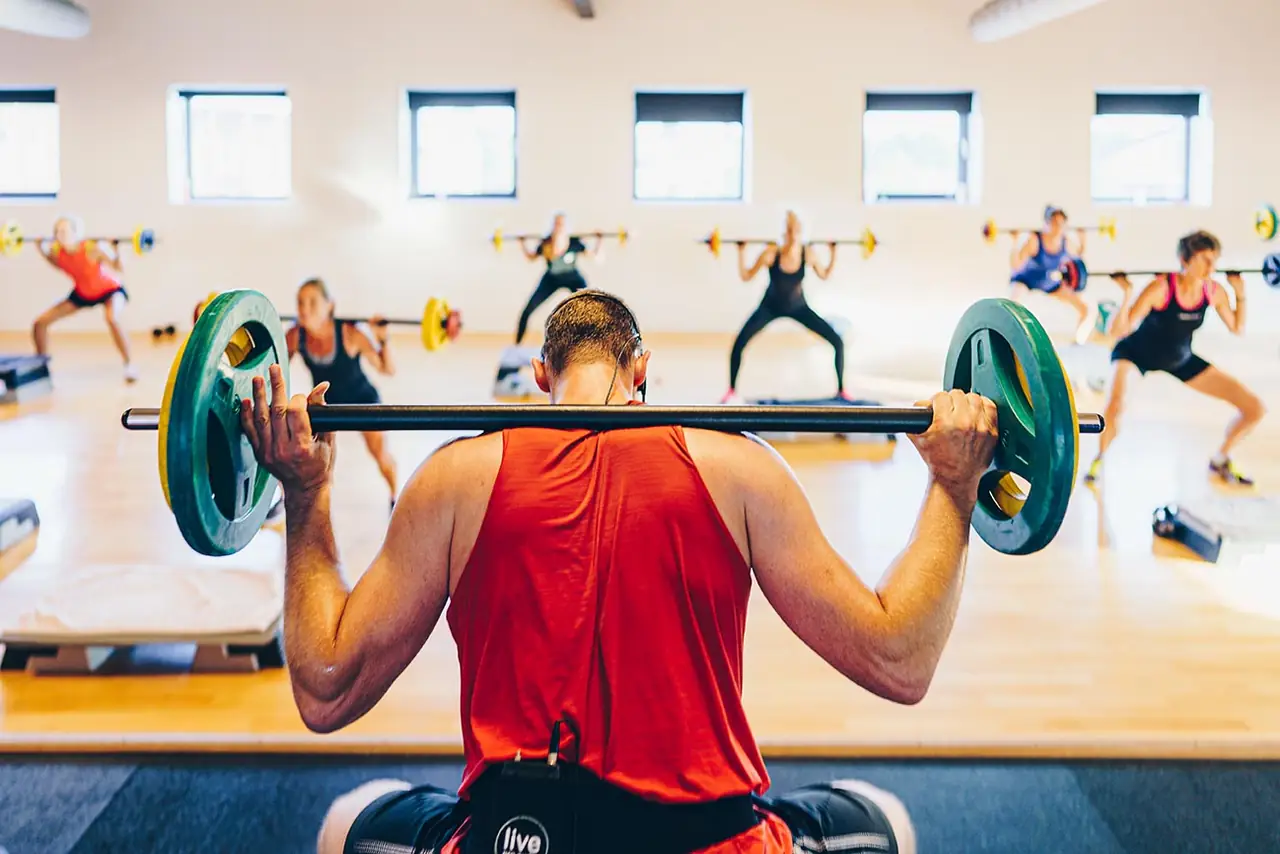 Deelnemer drukt een halter boven het hoofd tijdens Bodypump