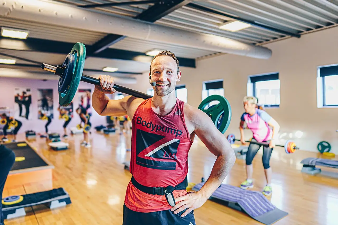Bodypumpinstructeur met een halter op de schouders