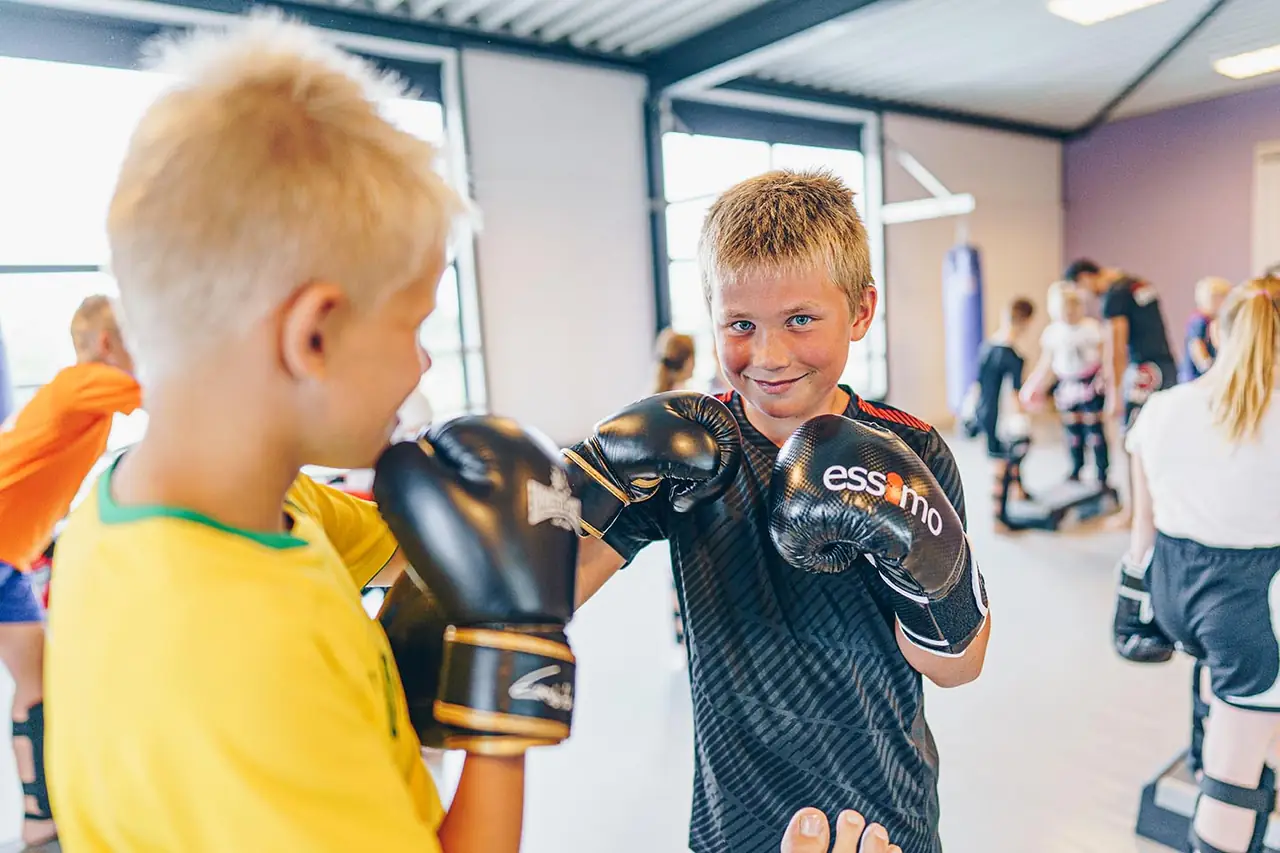 Twee jongens oefenen samen tijdens jeugdkickboksen