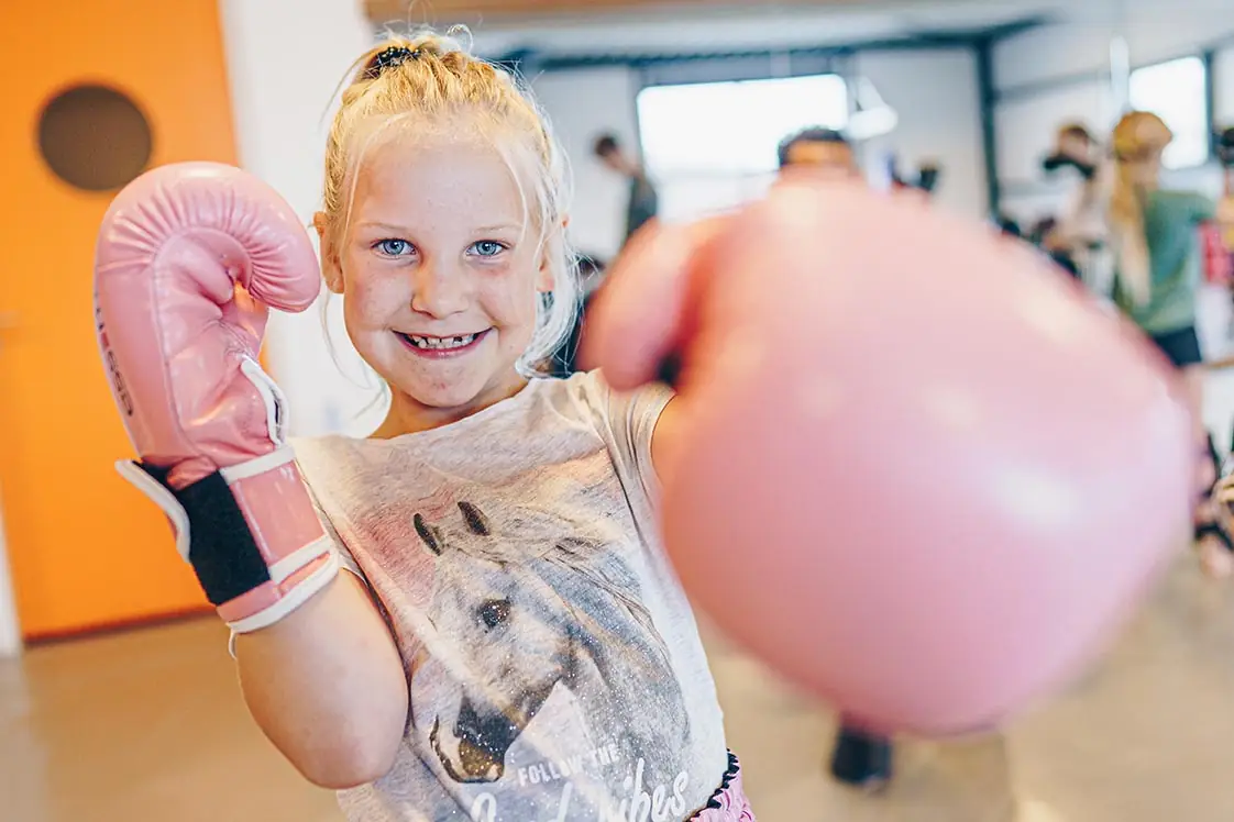 Meisje met roze bokshandschoenen tijdens jeugdkickboksen