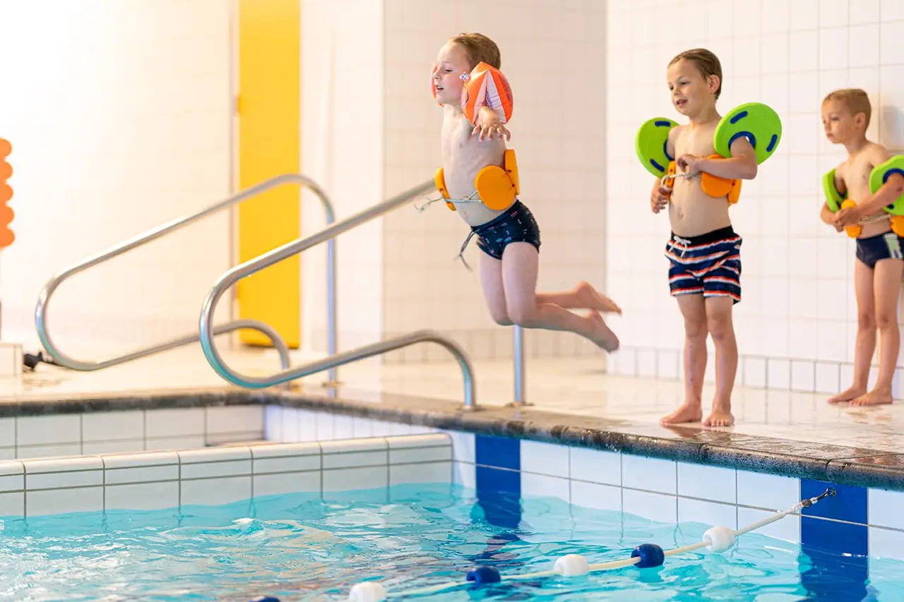 Kinderen springen van de kant tijdens zwemles