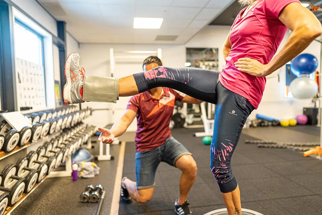 Personal trainer begeleidt een sporter bij een oefening