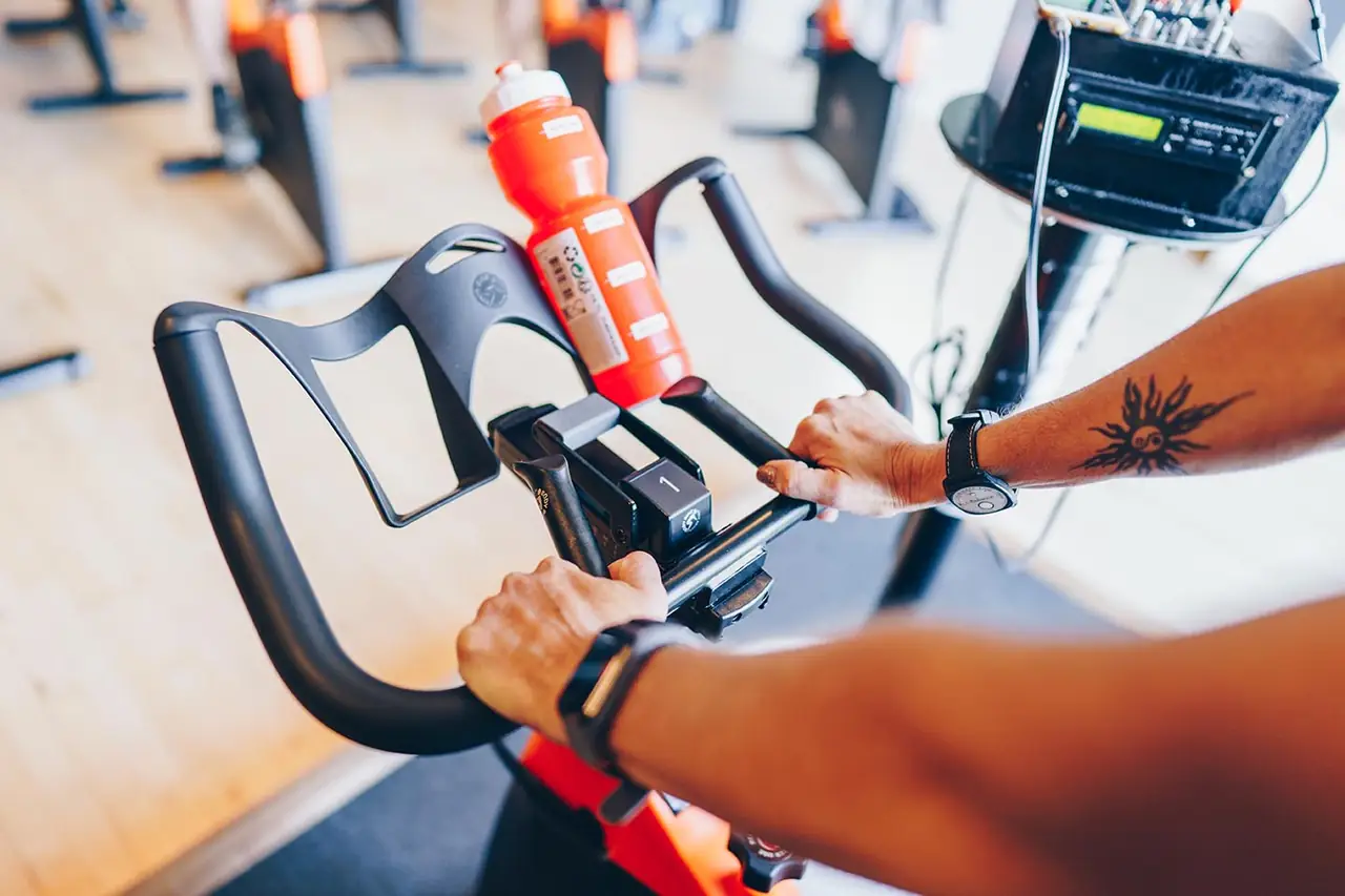 Handen aan het stuur van een spinningfiets