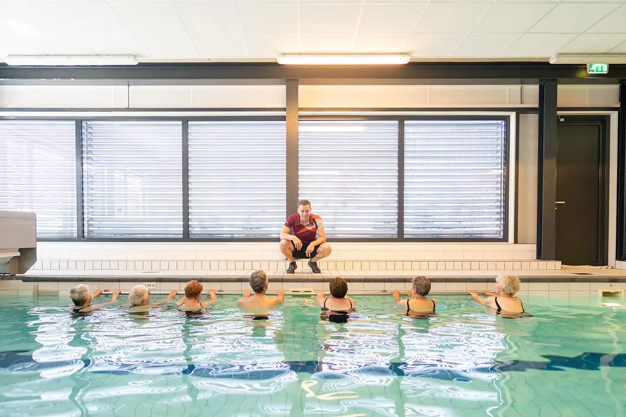 Instructeur geeft een les aan een groep in het zwembad
